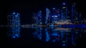 A stunning night view of a city skyline with illuminated skyscrapers reflecting on calm water.