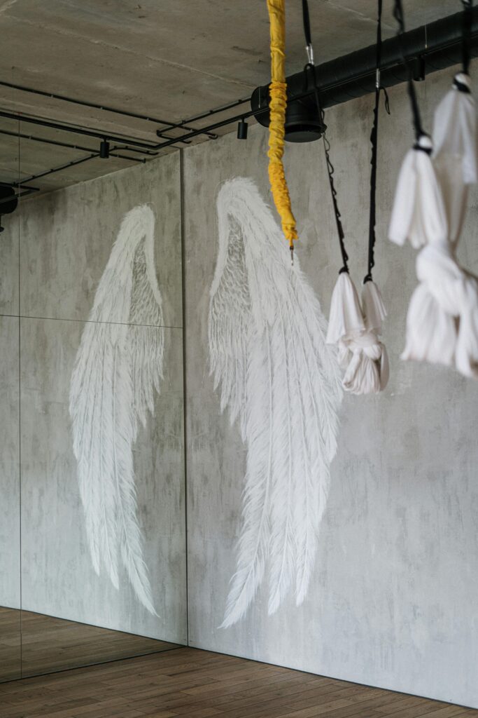 Serene indoor yoga studio featuring angel wing art on walls.
