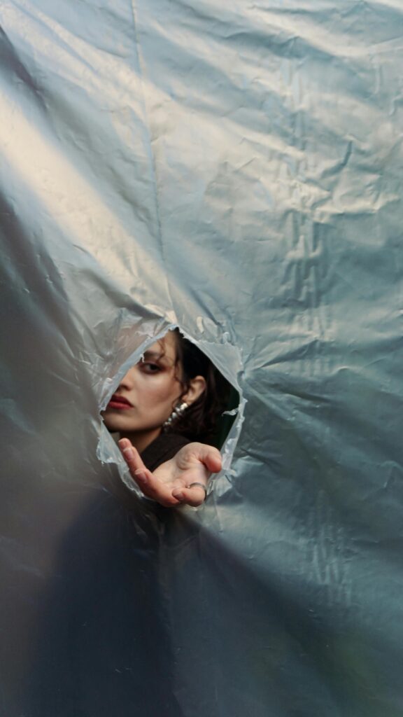 A person peers through a hole in a fabric, adding mystery and intrigue.